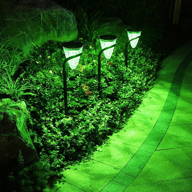 Outdoor solar lights illuminating a garden path with vibrant green colors.