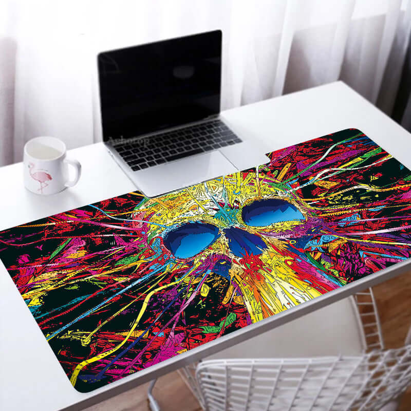 Custom Large Gaming Mouse Pad with vibrant skull design on a desk beside a laptop.