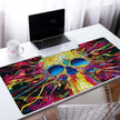 Custom Large Gaming Mouse Pad with vibrant skull design on a desk beside a laptop.