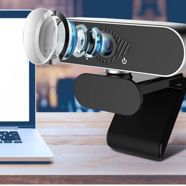 Webcam with microphone showcasing its detailed lens setup next to a laptop for video calls.
