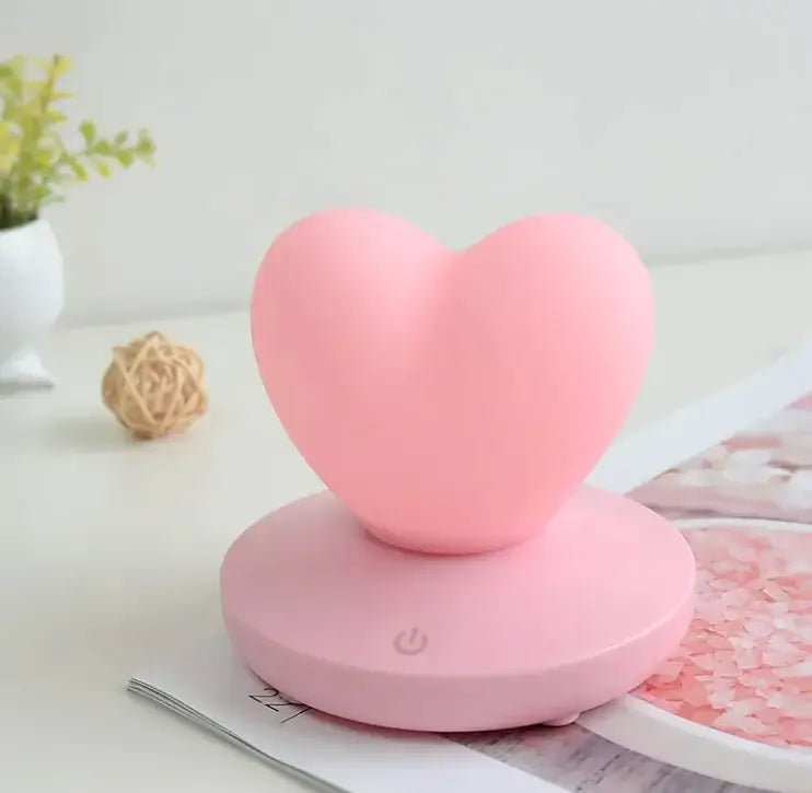 GlowTouch Desk Lamp in a heart shape, pink color, providing soft illumination and modern style for any workspace.