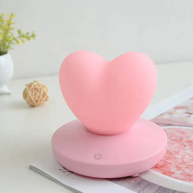 GlowTouch Desk Lamp in a heart shape, pink color, providing soft illumination and modern style for any workspace.