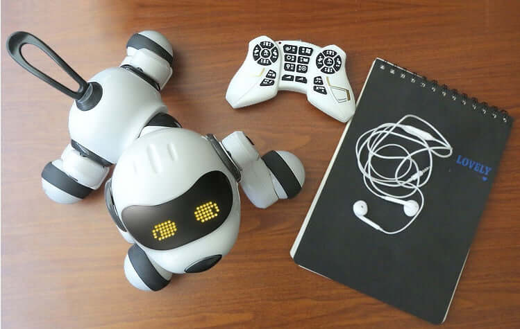 Intelligent Remote Control Robot Dog with game controller and notepad on wooden table.