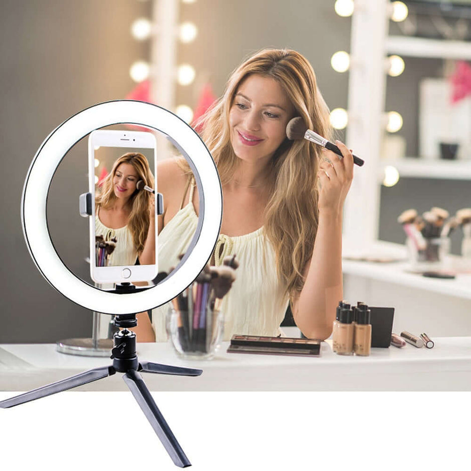 Woman using a Led Ring Light for makeup application in a brightly lit studio.