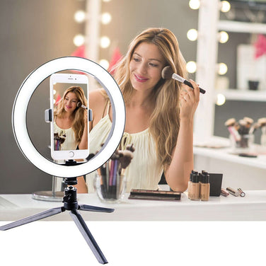 Woman using a Led Ring Light for makeup application in a brightly lit studio.