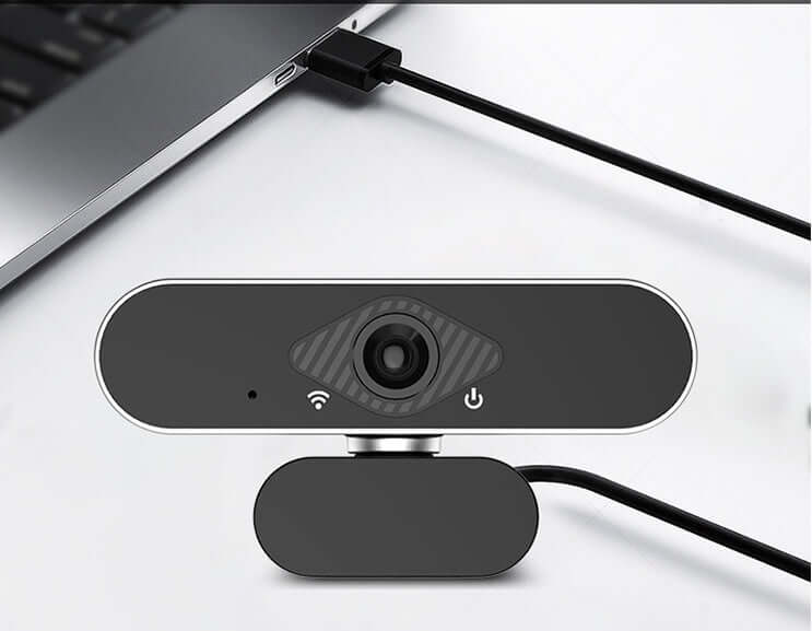 Webcam with microphone connected to a laptop, highlighting its sleek design and functionality for video calls.