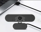 Webcam with microphone connected to a laptop, highlighting its sleek design and functionality for video calls.